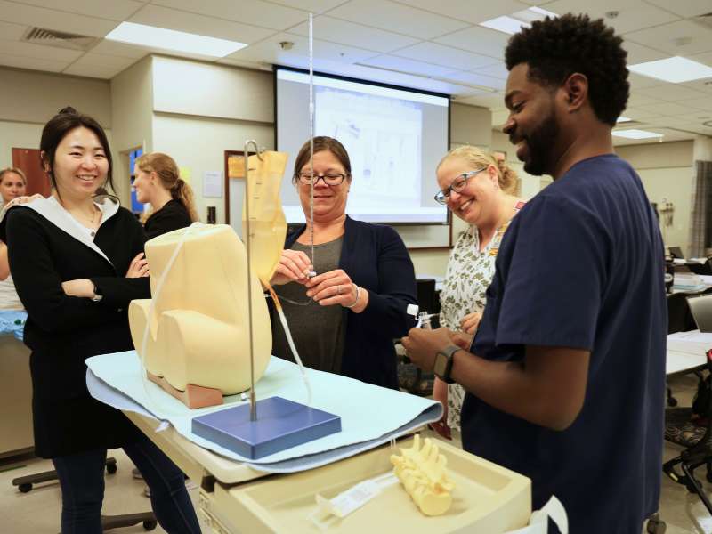 graduate nursing students practice and advance procedure with the guidance of a faculty member