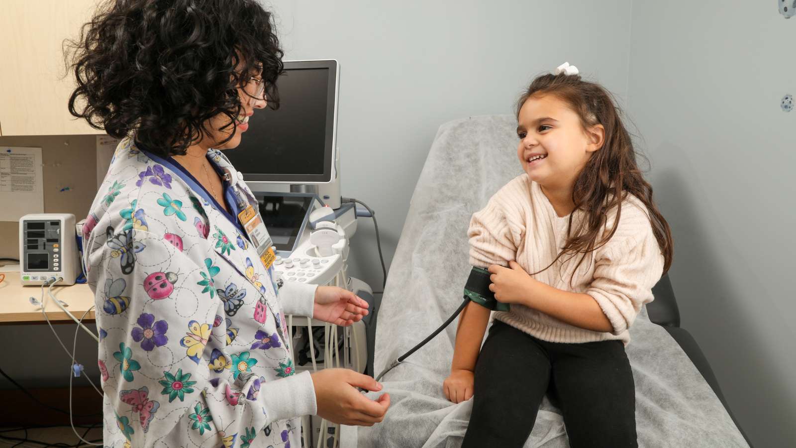 a clinical nurse researcher takes a blood pressure reading on a child participating in the RECOVER study