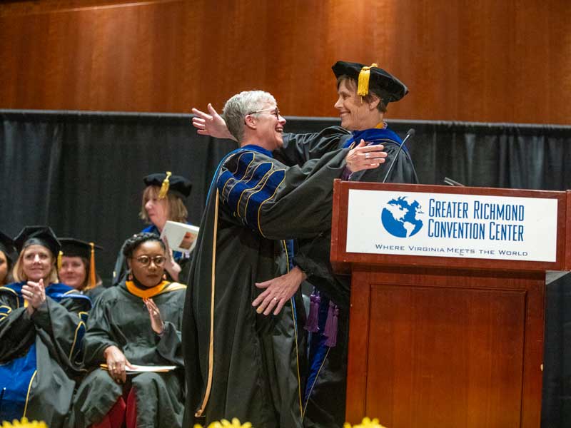 jo robins hugs dean jean giddens at a graduation ceremony